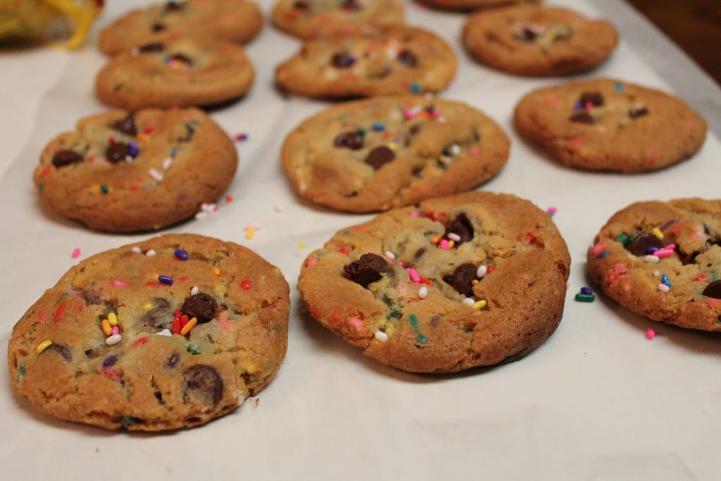 Rows of gooey cake batter chocolate chip cookies on a baking sheet lined with parchment paper. 