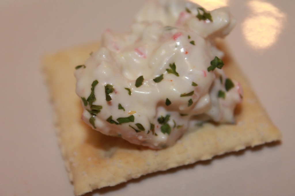 A small spoonful of creamy seafood salad on a saltine cracker. Crispy crackers or veggies are the best pairing for a creamy crab and shrimp salad!