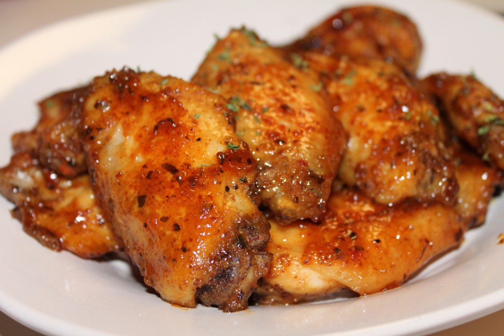 A plateful of Basil Honey Mustard wings covered in a sticky sauce and dried basil flakes. 