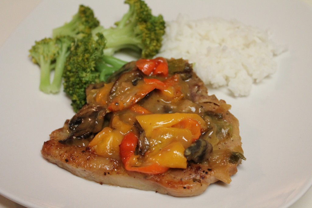 Golden smothered pork chops served alongside bright green broccoli and white rice.