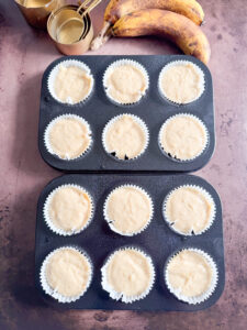 Paper liners in a muffin tin filled with muffin batter.