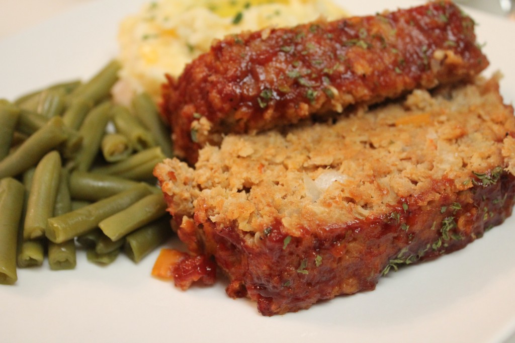 Moist and delicious turkey meatloaf with green beans and mashed potatoes served on a white dish. 