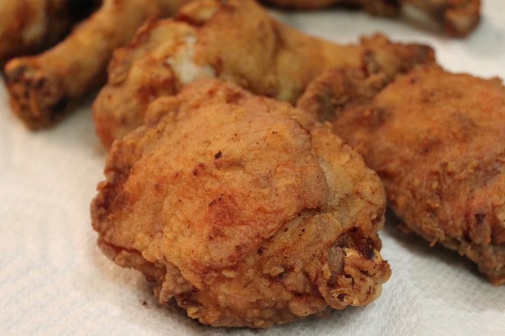 A close up of golden Southern fried chicken resting on a white paper towel. 