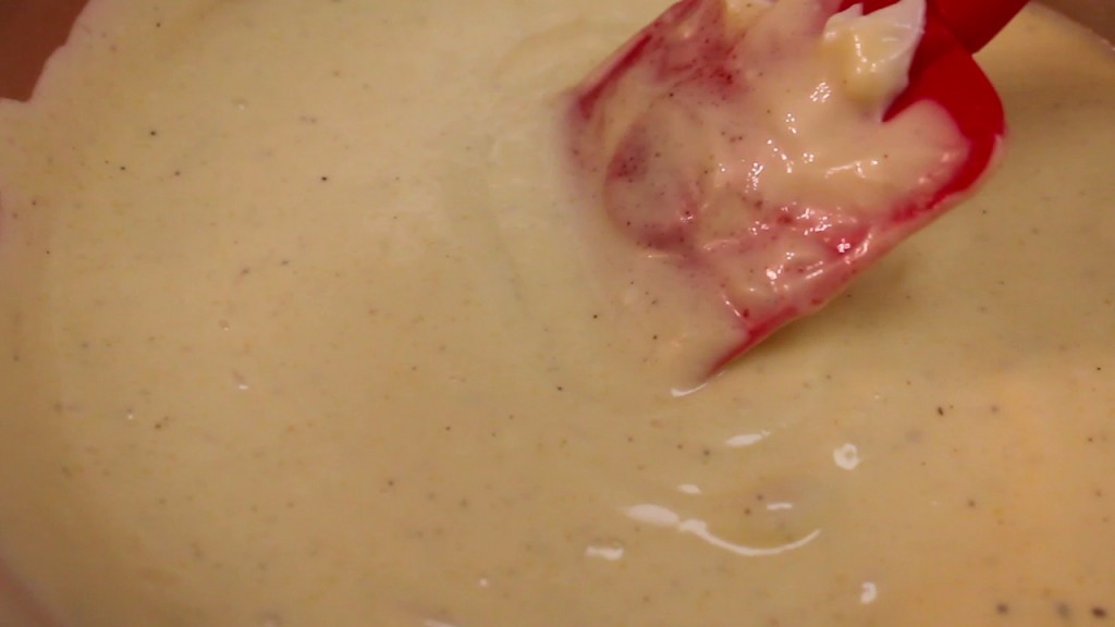 Creamy dressing in a bowl stirred with a red spatula. 