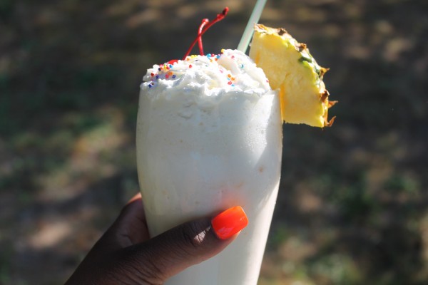A delicious pineapple and passion fruit milkshake topped with whipped cream, sprinkles, and a sweet pineapple slice