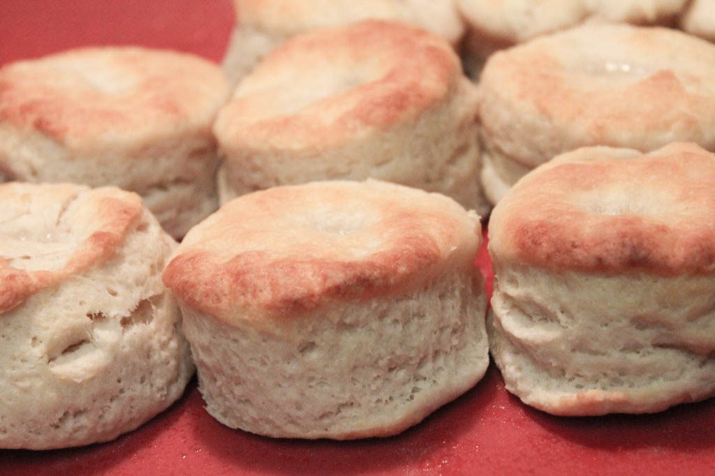 A close-up of rows of golden buttermilk biscuits on a red platter. 