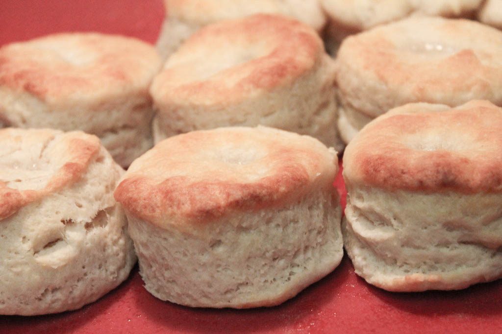 A close-up of rows of golden southern buttermilk biscuits on a red platter. 