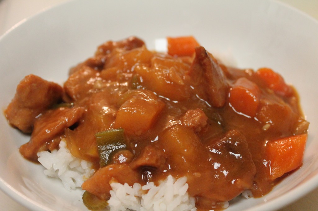 Tender Sweet and Sour Pork on a bed of white rice served in a shallow white bowl.