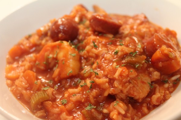 Jambalaya Stew fills a white bowl. Tender shrimp, chicken and sausage are mixed with rice and veggies in a comforting broth.