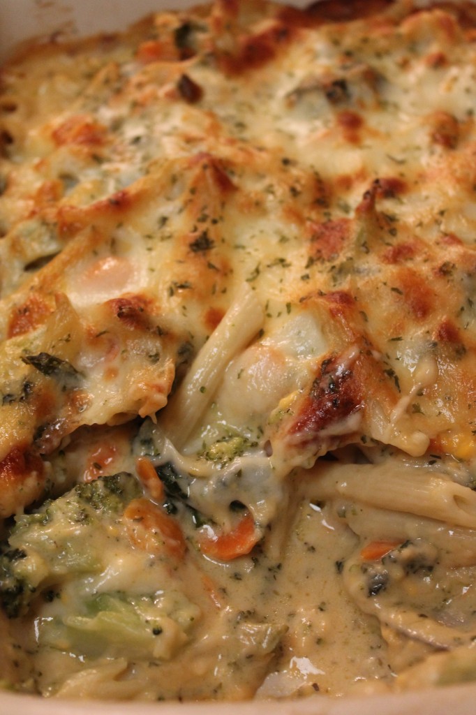 A close up of creamy cheese sauce, tender pasta and broccoli and carrots.