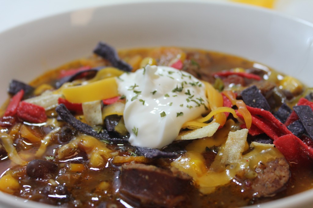 Sausage Tortilla Soup dolloped with sour cream and served in a white bowl.