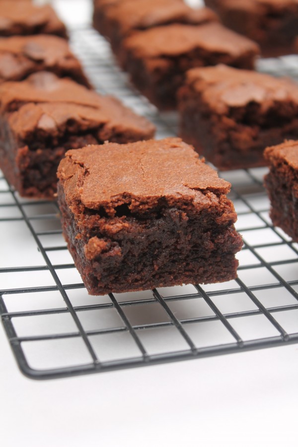 A close-up image showing moist homemade brownies with a crisp chocolatey top. 