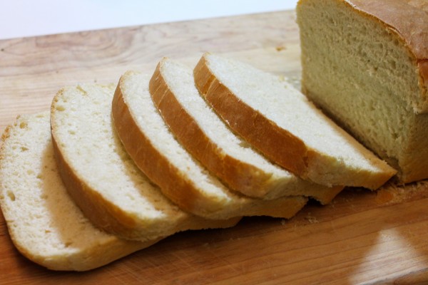 A loaf of homemade white bread on a cutting board, sliced into five sandwich-size slices, perfect for toast, sandwiches, and more.