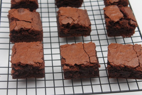 Rows of moist, decadent homemade brownies cooling on a black wire rack.