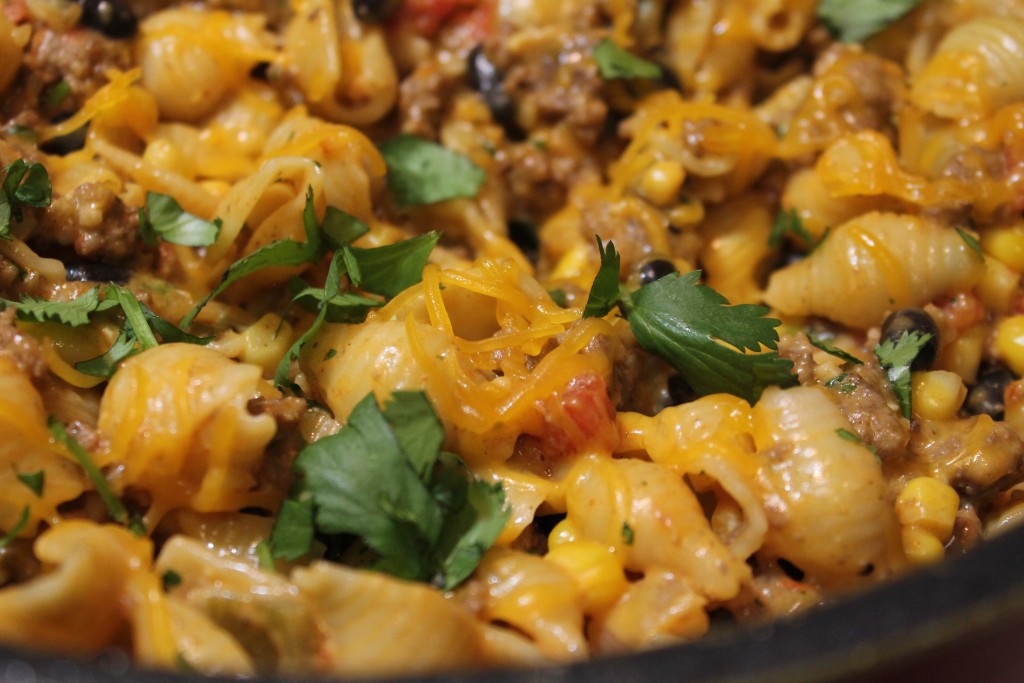 A skillet filled with cheesy Southwestern pasta garnished with fresh cilantro. 