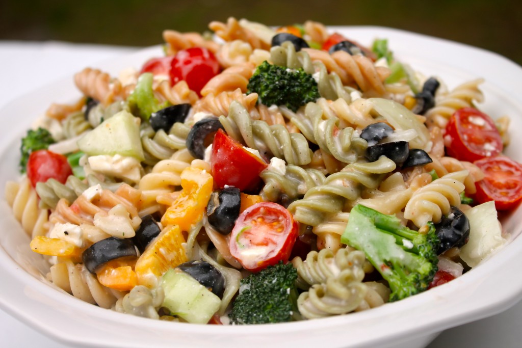 Colorful Italian pasta salad served in a white serving dish. 