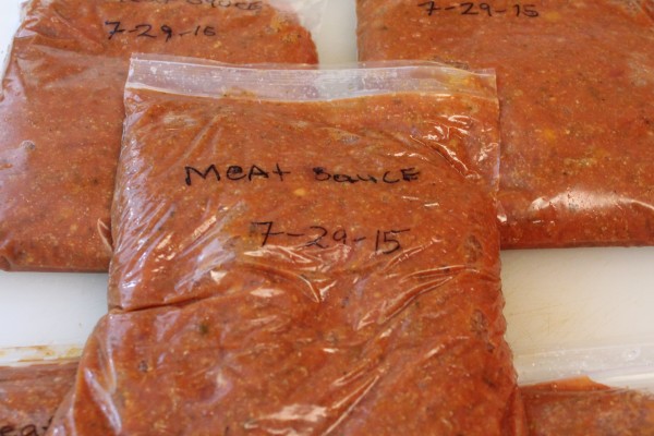 Plastic freezer bags filled with fresh homemade meat sauce. Each bag is labeled with “meat sauce” and the date written in black marker.