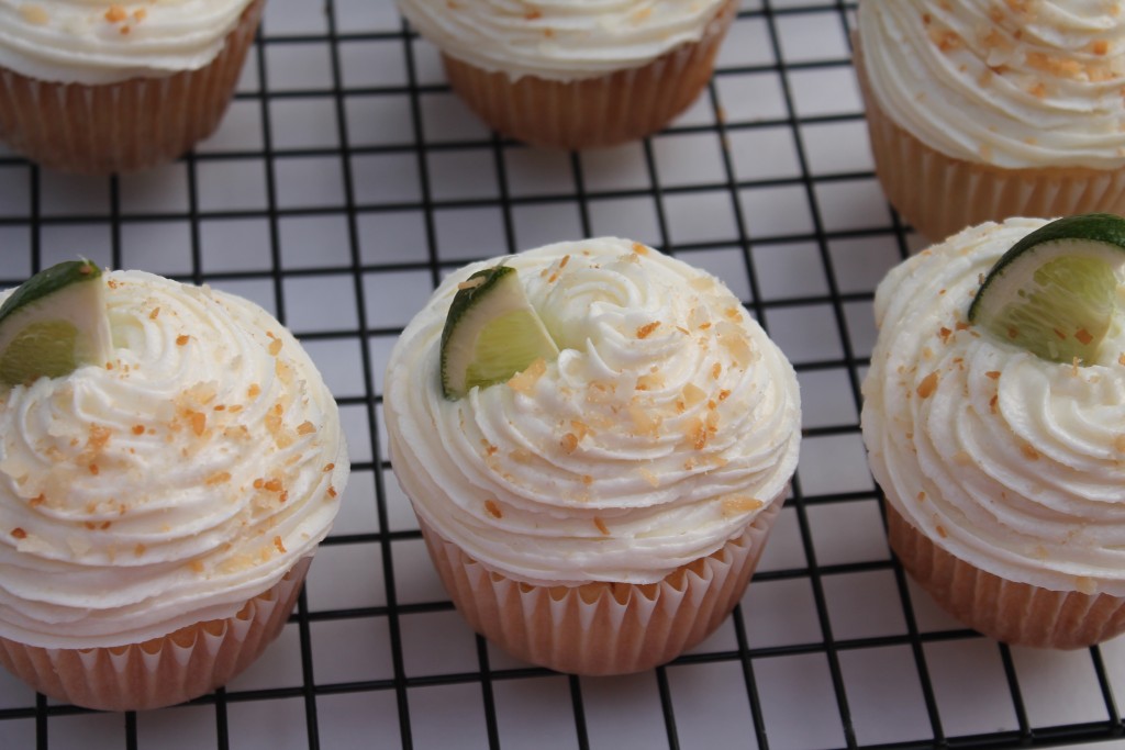 Two rows of three Coconut Lime Cupcakes on a black wire cooling rack.