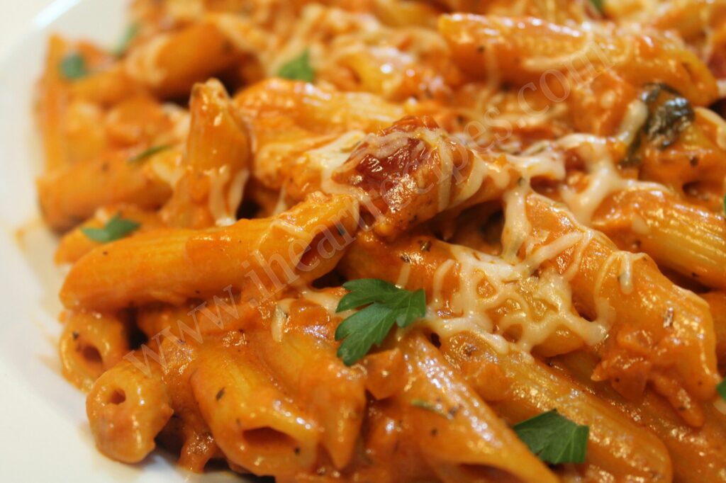 A close up of tender penne pasta covered in creamy vodka sauce, melted shredded cheese and fresh parsley. This penne with homemade vodka sauce is the perfect date night meal!