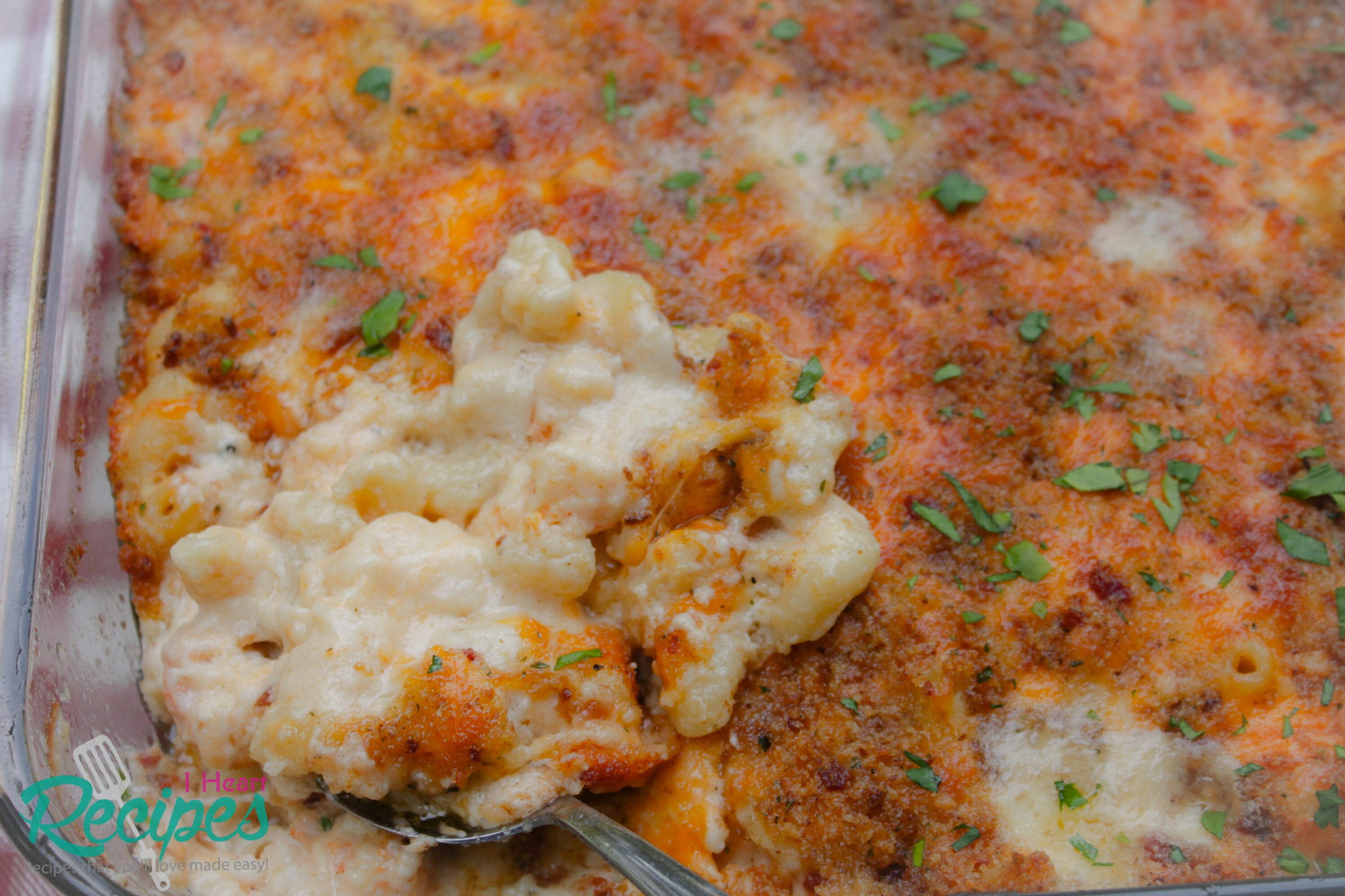 A close up image of a glass casserole dish filled with creamy homemade lobster mac and cheese. Tender pasta covered in a homemade cheese sauce and topped with golden brown bacon breadcrumb topping.