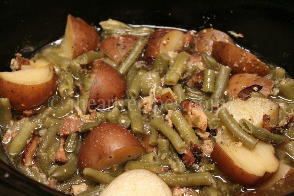 A Crockpot filled with tender Southern Green Beans with halved red potatoes in a savory broth. 