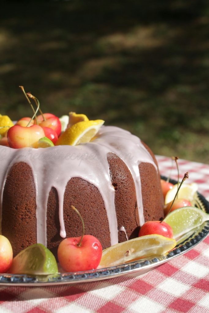 A sweet Cherry 7Up Cake drizzled with icing and garnished with fresh cherries, lemons and limes. 