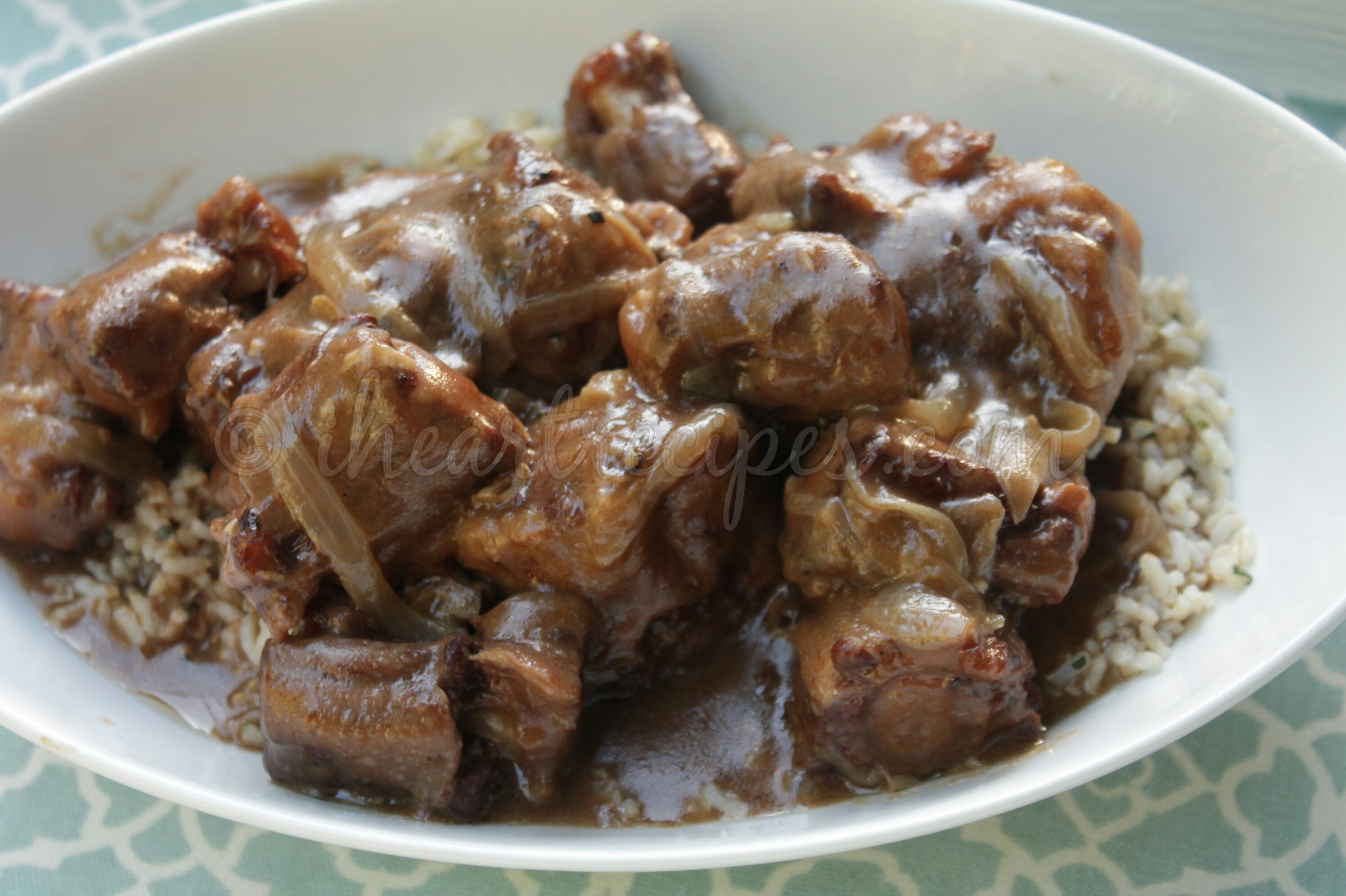 A platter of slow cooker smothered oxtails served over rice, smothered in a rich onion and garlic gravy.