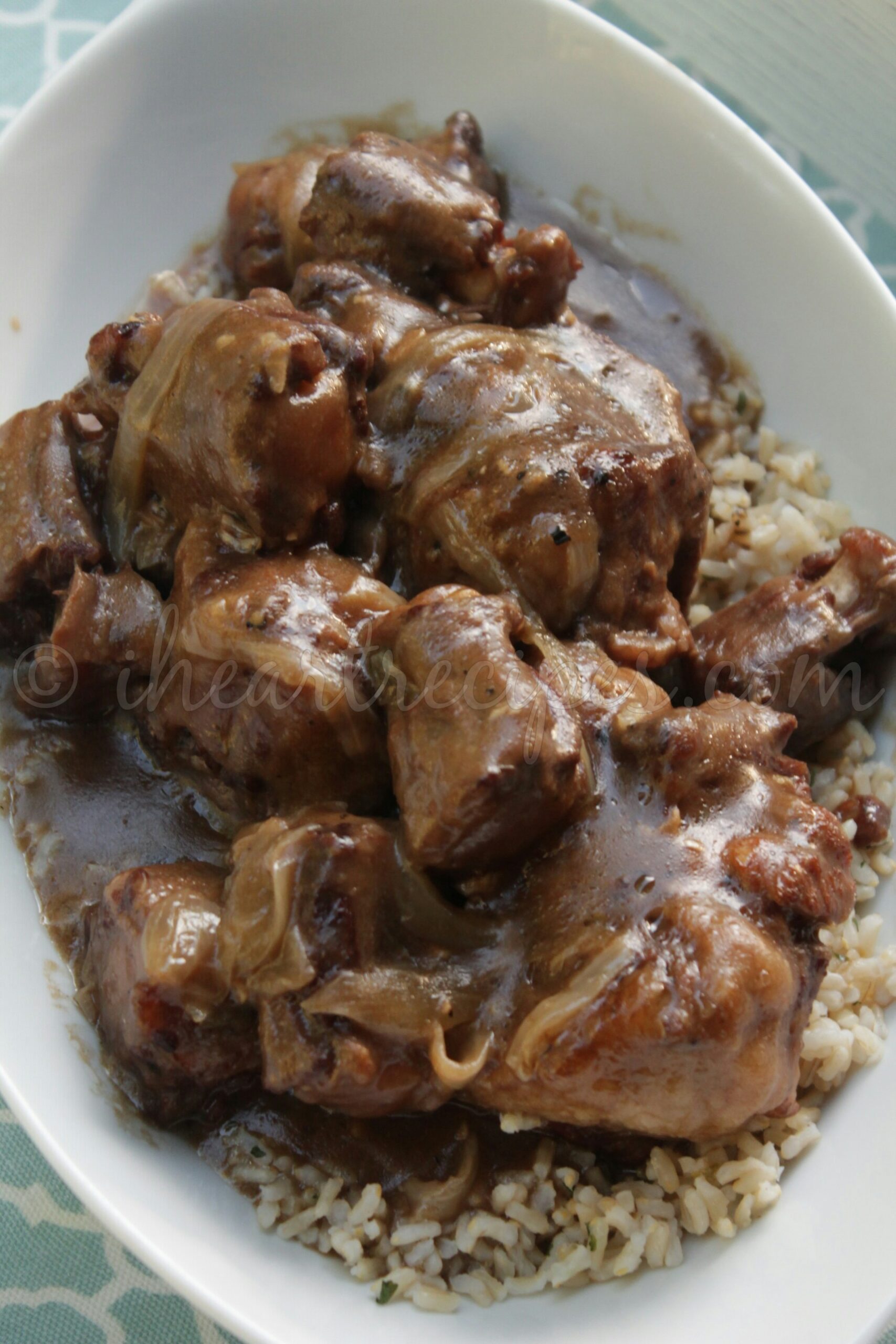 An overhead image of slow-cooked beef oxtails smothered in a thick onion and garlic gravy and served over rice.