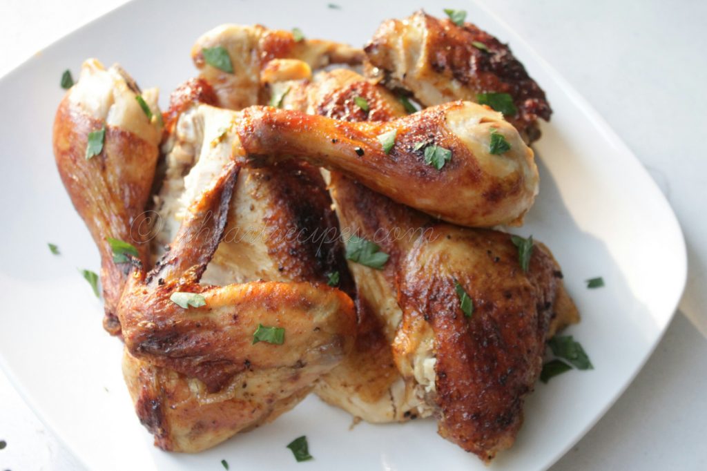 A simple spatchcocked roasted chicken is on a white square platter. The golden brown chicken skin is sprinkled with green herbs. 
