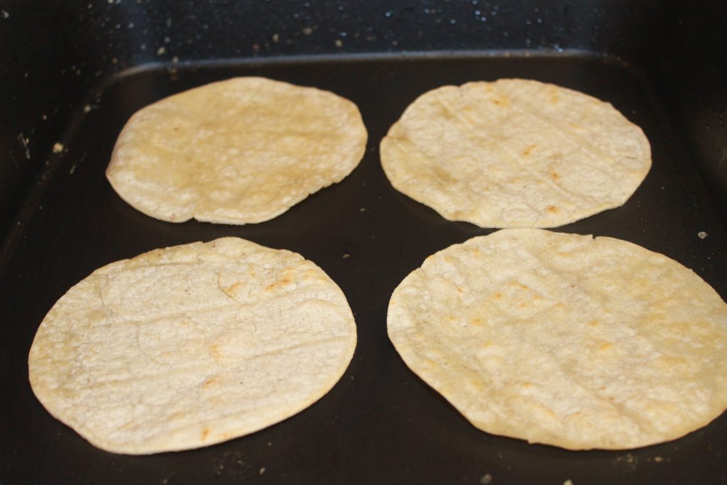 Four corn tortillas warming on the stove. 