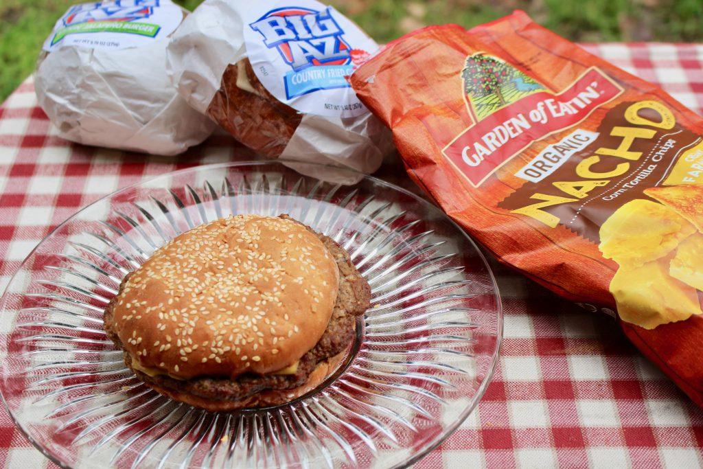 Cheeseburgers and chips served on a red and white checked picnic blanket for game day!