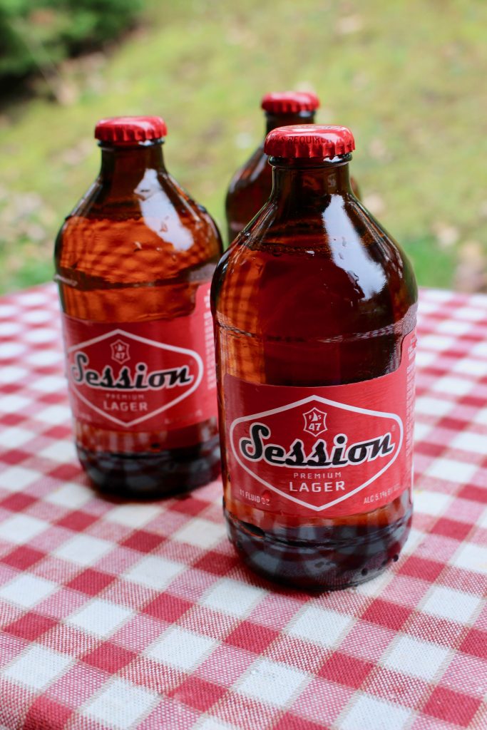 Session Lager bottles arranged on a red and white checked tablecloth. This beer comes in cool vintage-style bottles and hits the spot on game day!