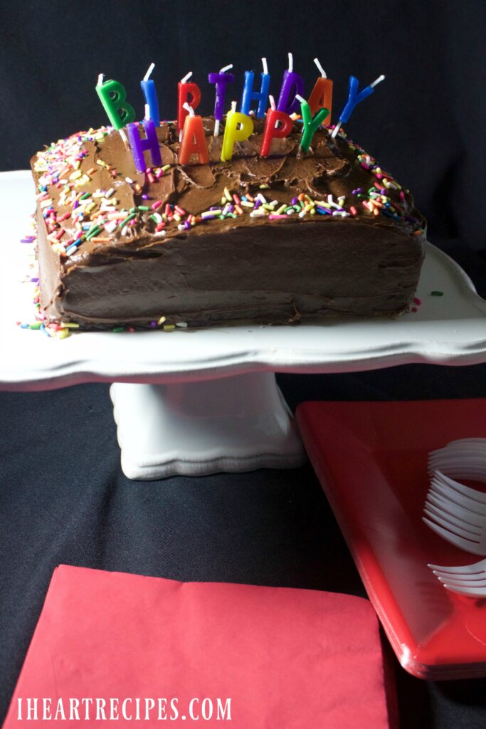 A moist, chocolate birthday cake on a classic white scalloped cake pedestal. Head to your local Dollar Tree to help you out with this Simple Birthday Cake Recipe.