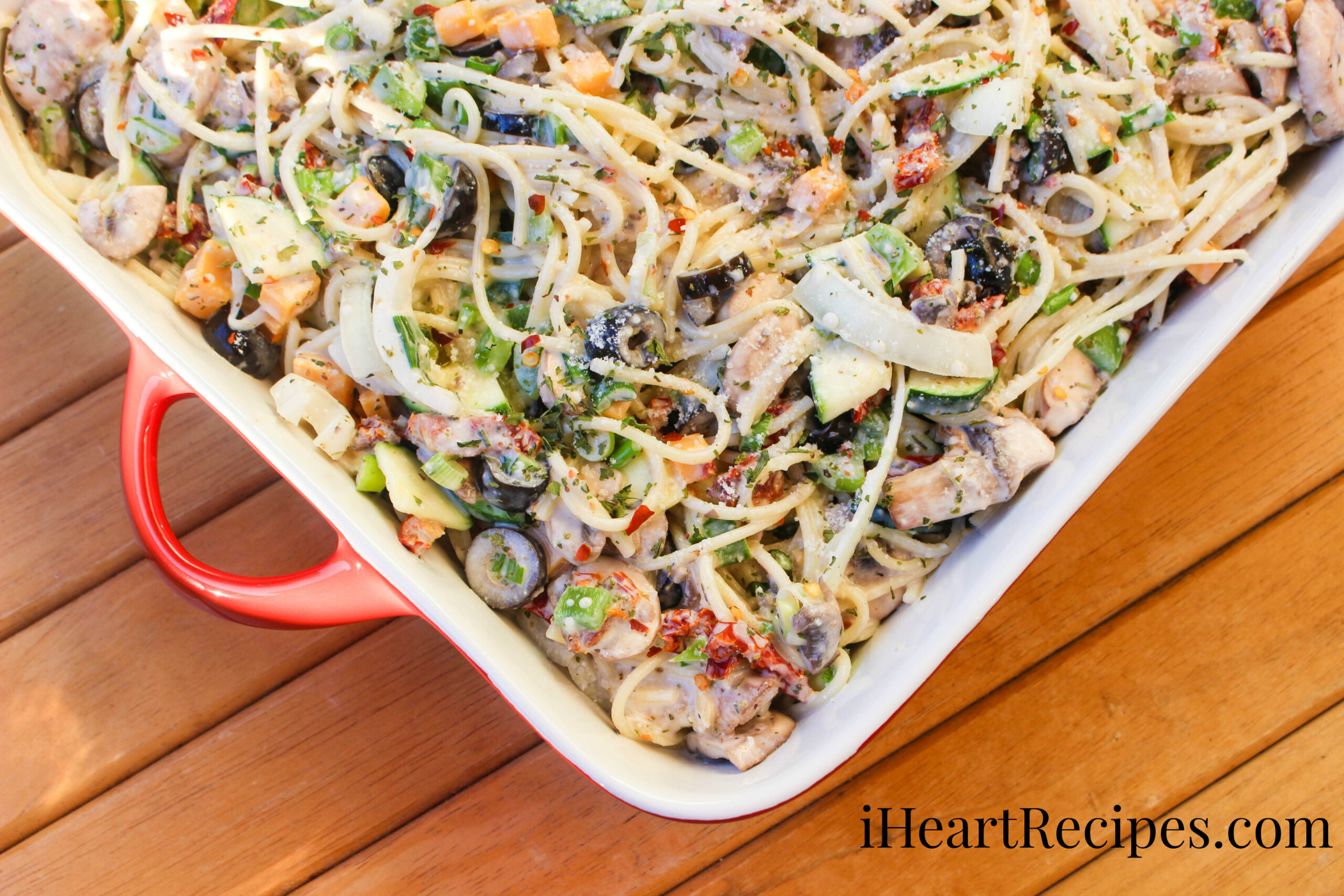 A red serving dish filled to the brim with Creamy Spaghetti Pasta Salad.