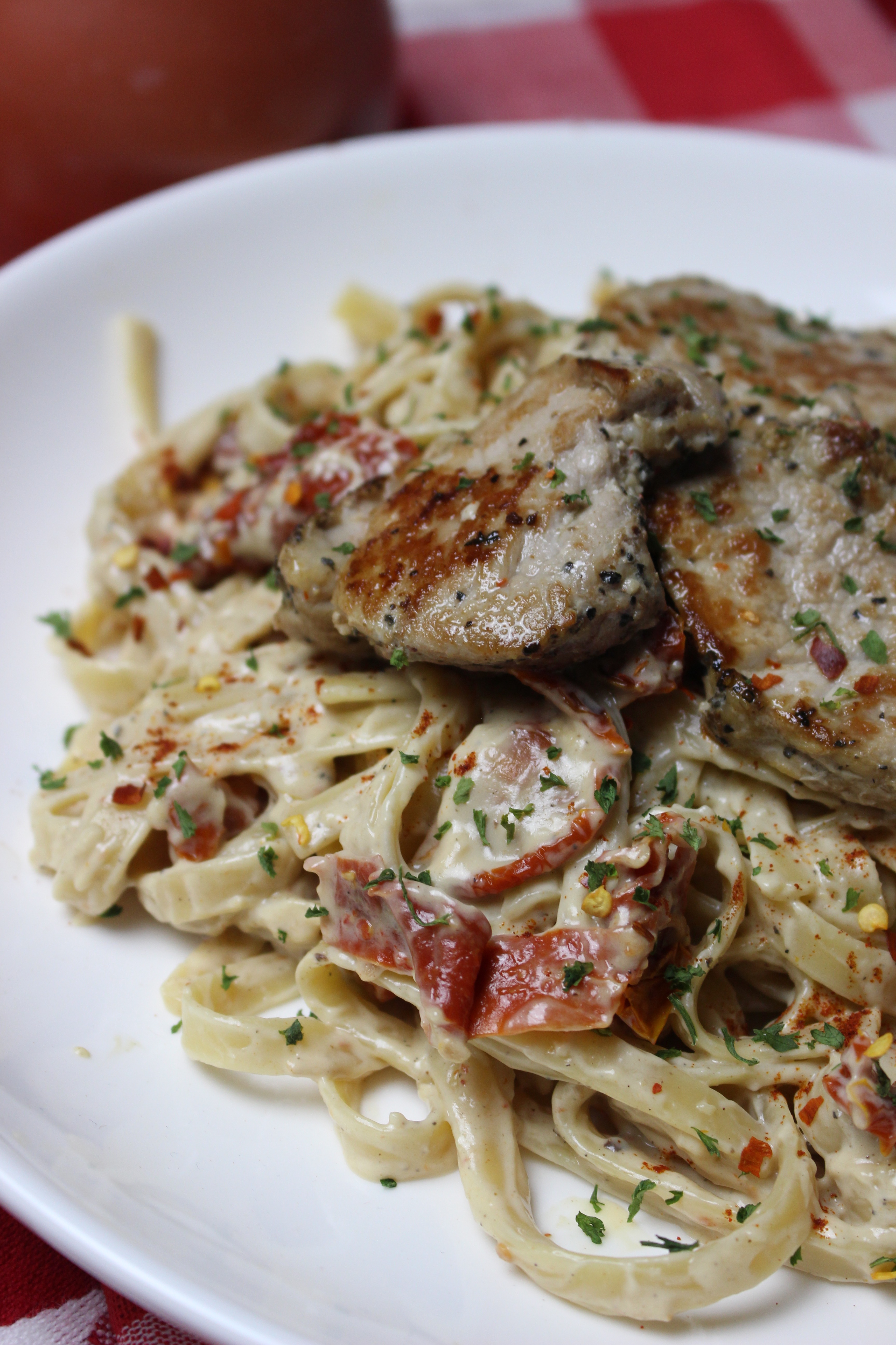 Savory grilled pork and sun dried tomatoes Alfredo on a bed of tender pasta sprinkled with red pepper flakes. A great date-night meal for two!