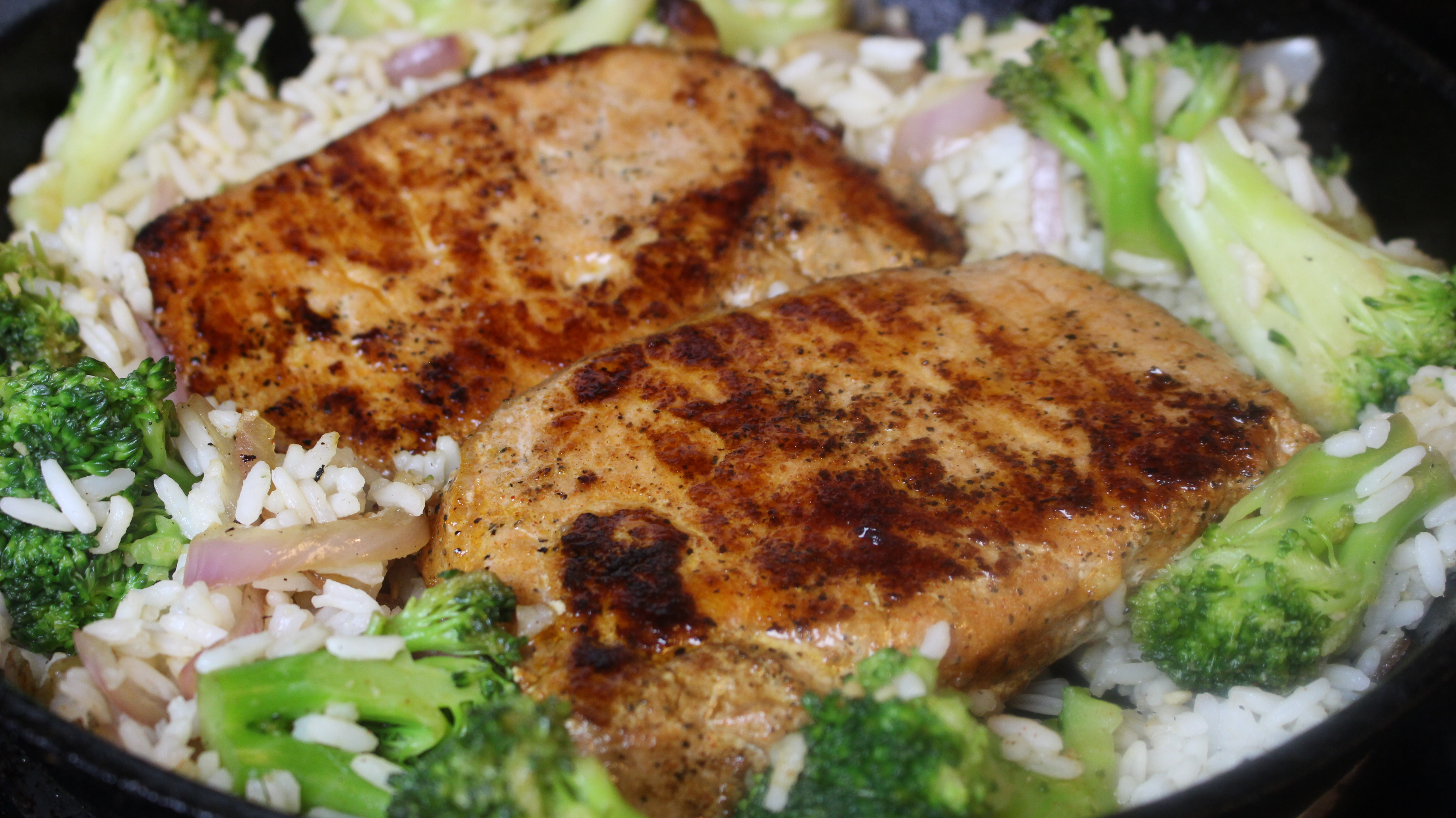 Savory pork chops with tender rice and broccoli served in a seasoned skillet. A simple, healthy dinner!