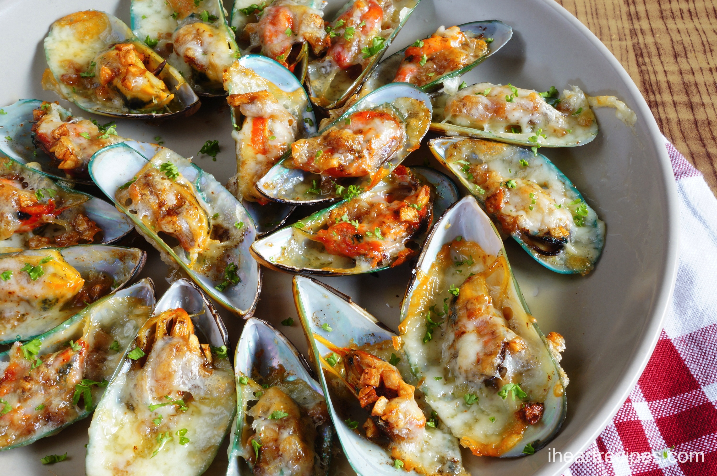 Delicious baked Cheesy Garlic Mussels served on a classic white plate. Wow your guests with this amazing recipe!