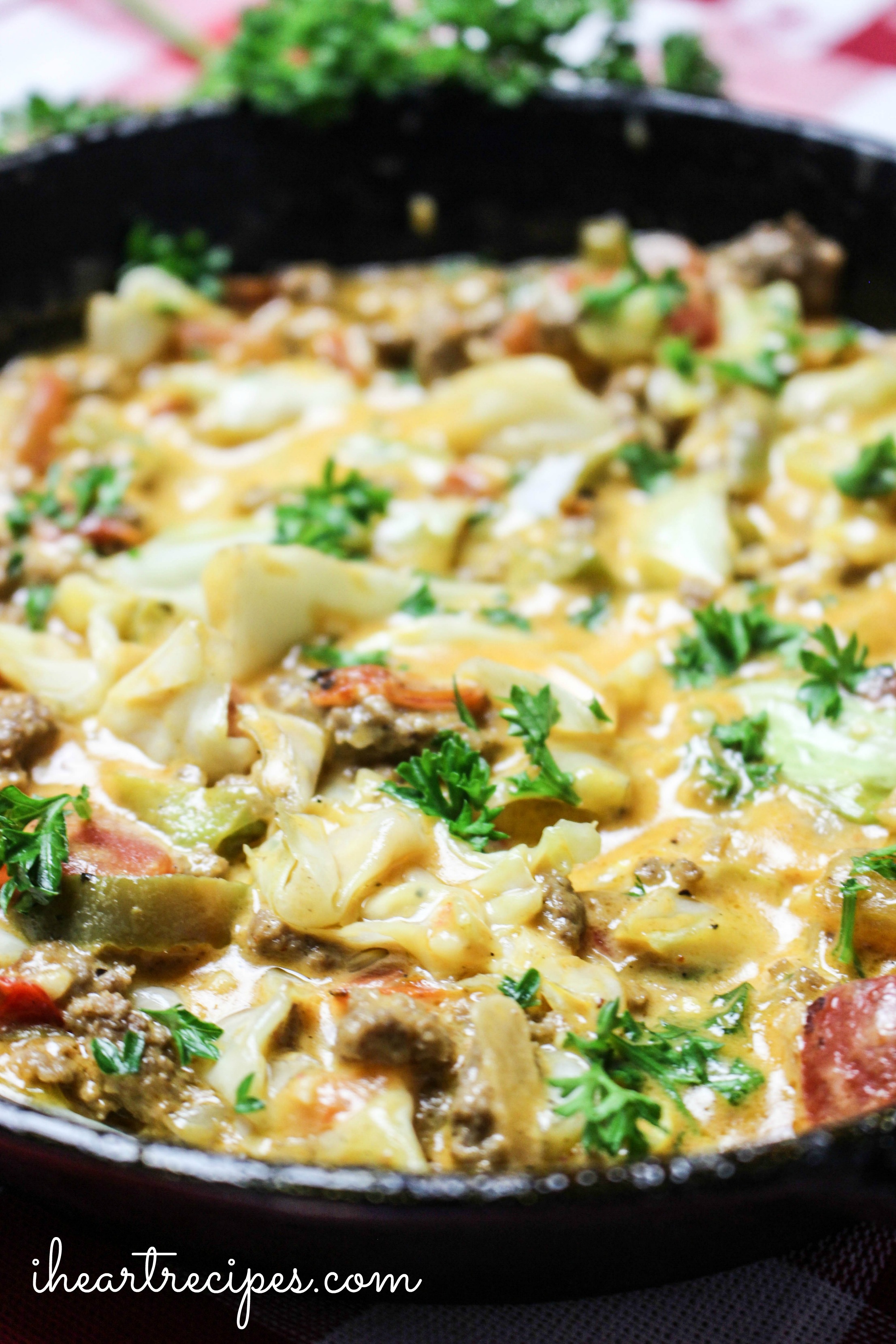 Creamy Cheesy Cabbage Creole topped with fresh green parsley in a cast iron skillet. This is a quick and easy weeknight meal.