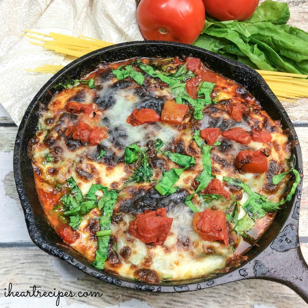 Easy chicken parmesan in a cast-iron skillet, topped with melty mozzarella and parmesan cheese, a hearty tomato sauce, and fresh basil.