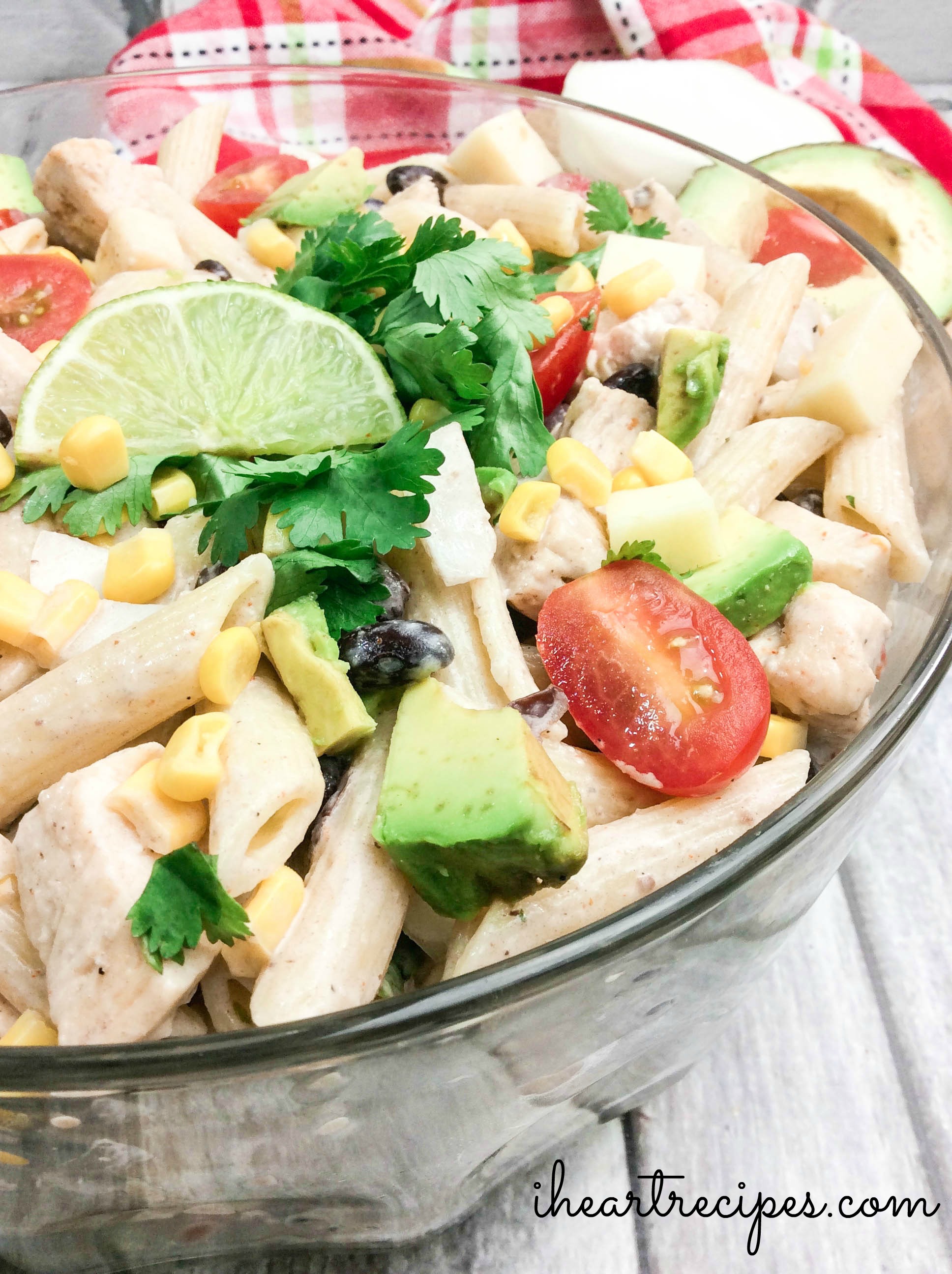 Colorful Cilantro Ranch Pasta Salad garnished with a lime wedge and bright green cilantro in a glass serving bowl. Layers of flavor!