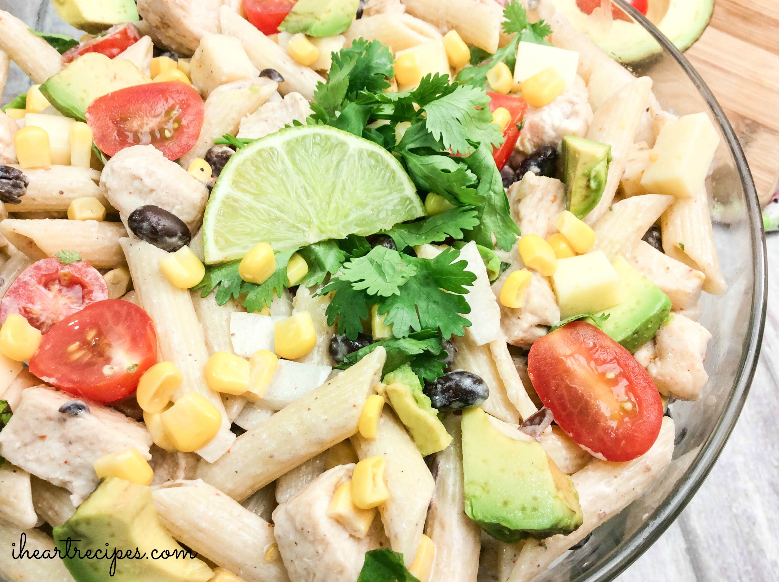 A creamy Cilantro Ranch Pasta Salad garnished with a tart lime wedge and a sprig of cilantro served in a glass serving bowl. This is perfect for the next summer get-together!