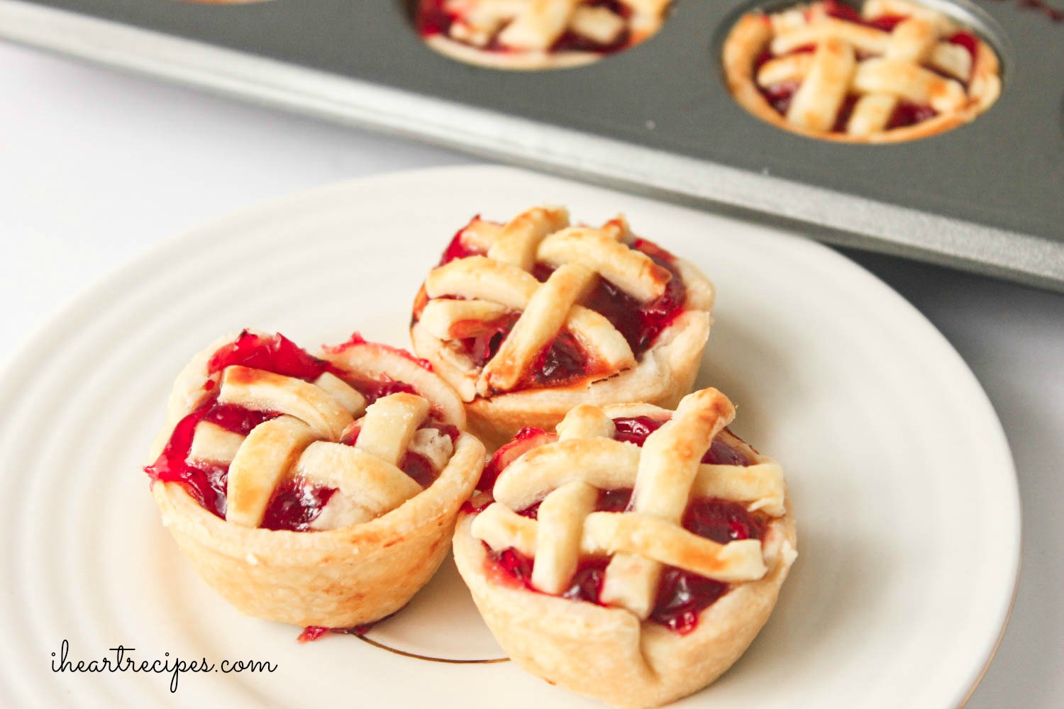 Three sweet mini cherry pies on a white plate. They are the perfect bite-sized summer treat!