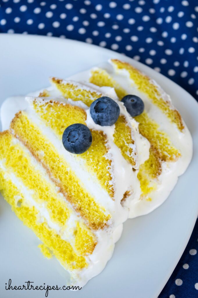 Thin slices of layered lemon ice cream cake topped with tender blueberries served on a classic white plate. So many flavors of summer!