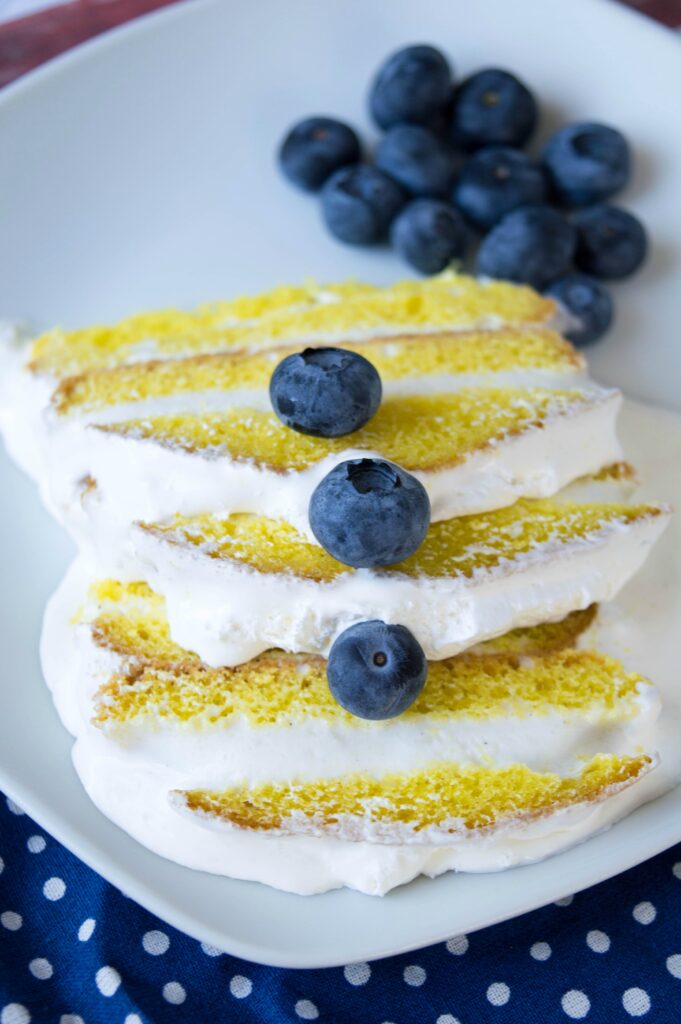 Three thin slices of lemon cake layered with vanilla ice cream and topped with fresh blueberries for garnish.