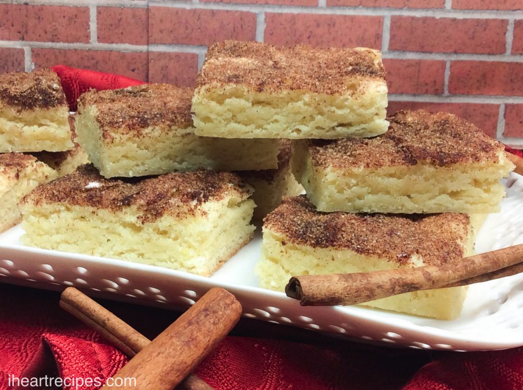 Chewy Snickerdoodles Bars piled high, garnished with sweet cinnamon sticks, served on an elegant white platter.