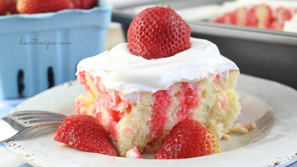 A delicious piece of strawberry poke cake topped with sweet whipped cream and fresh strawberries. What a refreshing treat!