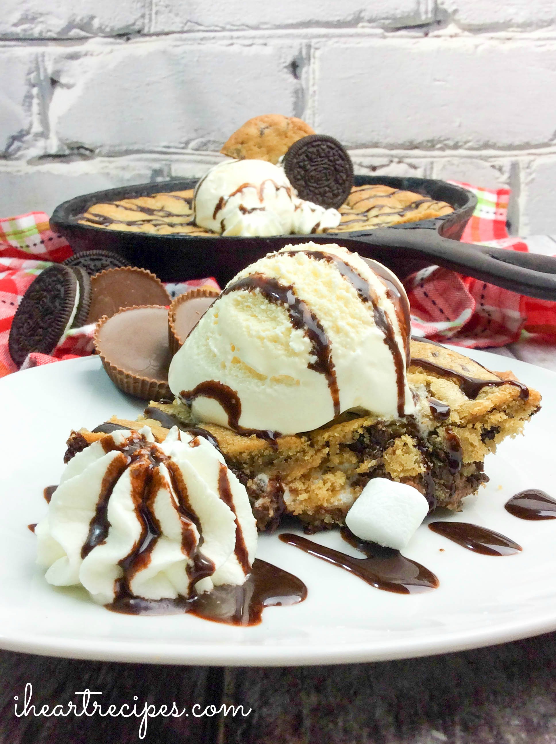 A warm and gooey Oreo & Reese's cookie topped with sweetness served on a white plate. This is the ultimate dessert!