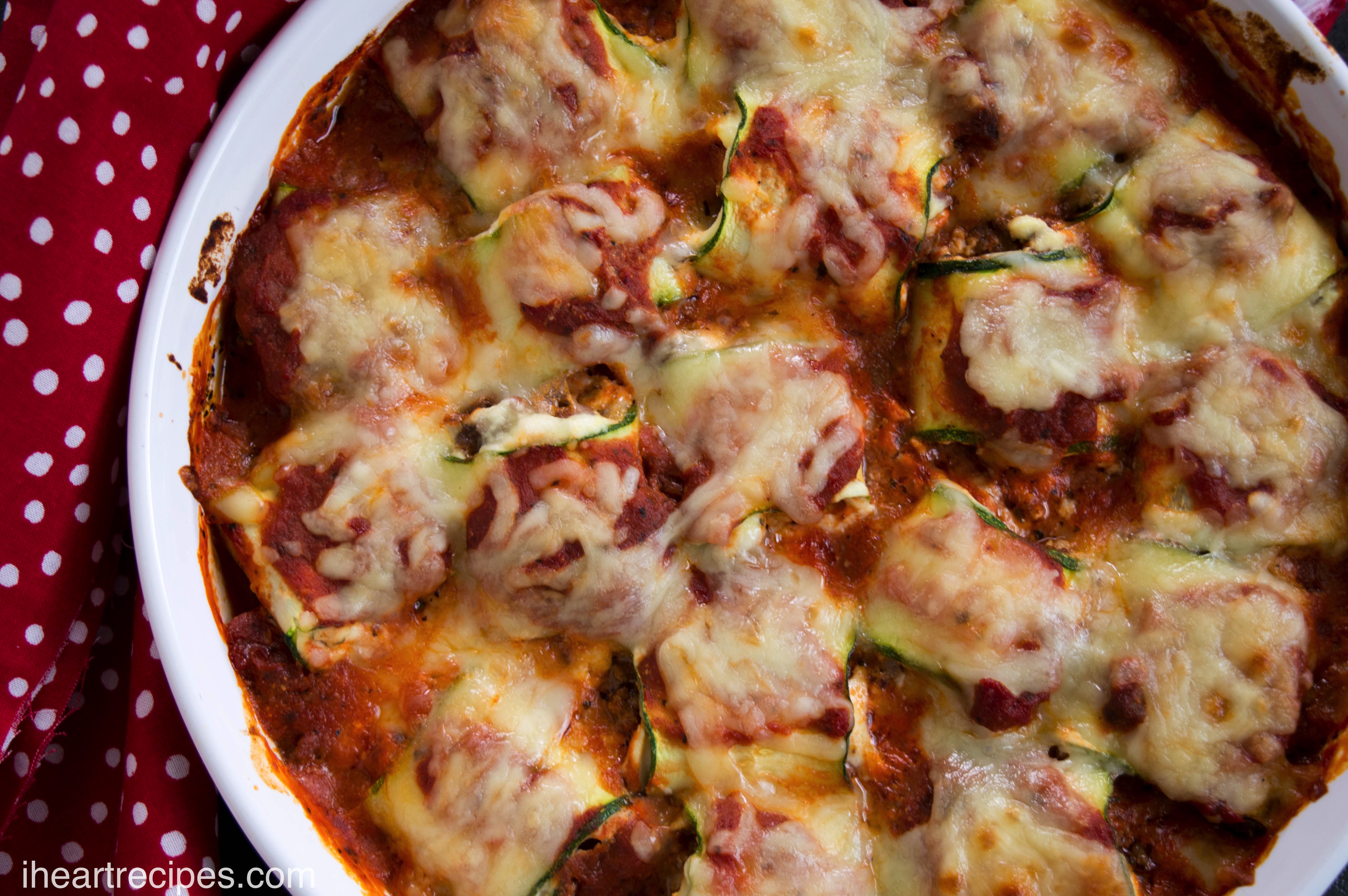 Tender and savory zucchini rollups simmering in hearty marinara sauce inside a classic white baking dish.