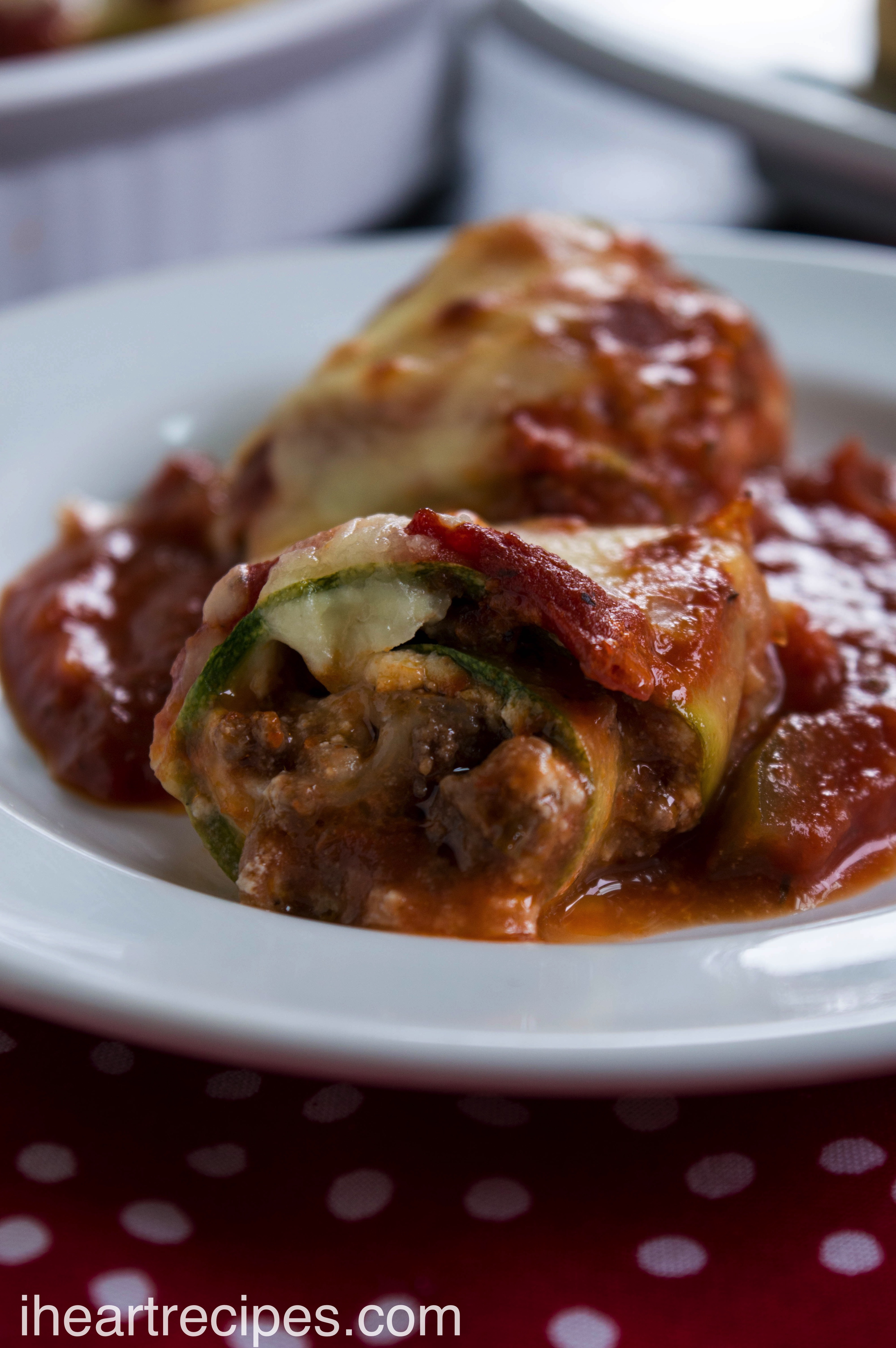 Tender meat and creamy cheese enveloped in a ribbon of zucchini served on a classic white plate.