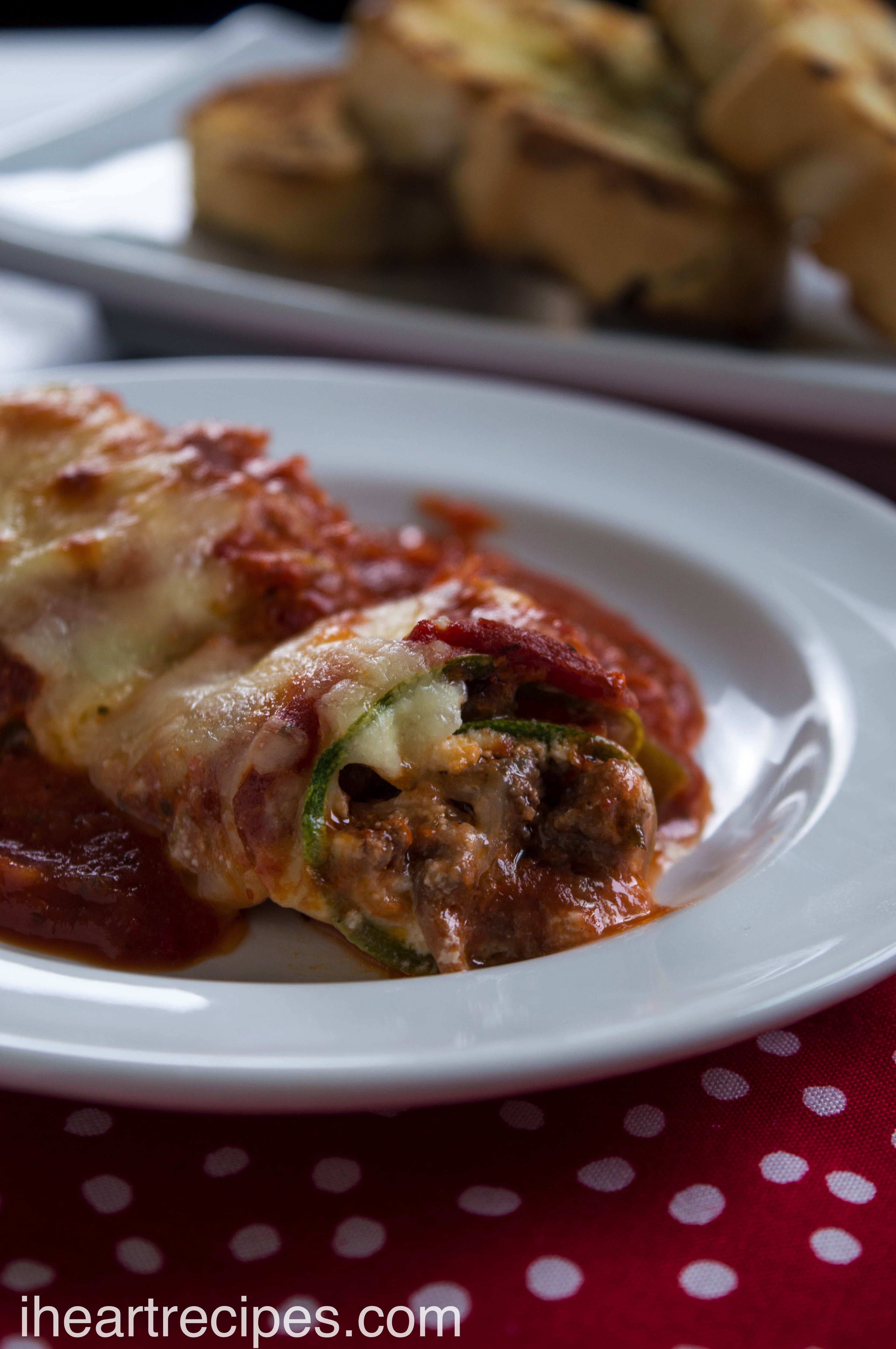Tender zucchini wrapped around savory filling, topped with flavorful marinara sauce, served on a classic white plate. 